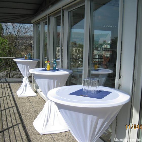 Eingedeckte Stehtische mit weißen Hussen auf einer Terrasse