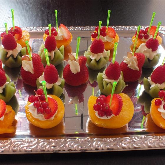Obst-Dessert mit Himbeeren, Kiwi und Sahne auf einem Silbertablett